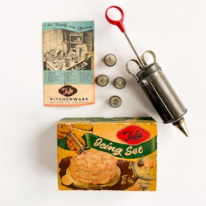 Könnte beinhalten: Vintage Tala Icing Set mit einer Metallspritze, verschiedenen Metalltüllen und einer Box mit Kuchenillustration. Das Set enthält ein Booklet mit dem Text "For Beauty and Efficiency" und "Tala Kitchenware".