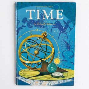 May include: A blue hardcover book titled A Maxton Book About TIME by William M. Hutchinson. The cover features a gold armillary sphere, a yellow sundial, a small pocket watch, and illustrations of zodiac constellations against a blue background.
