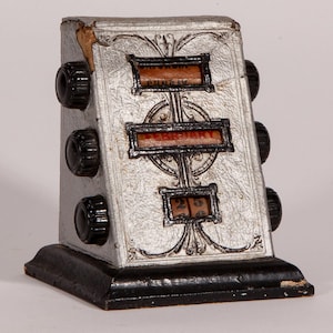 May include: An antique silver-colored perpetual calendar with black knobs and base. The calendar displays the month of February and the date 25. The design includes decorative scrollwork and a textured finish, giving it a vintage appearance.