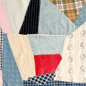 May include: A patchwork quilt with a variety of fabric patterns and colors. The quilt features sections of pink, blue, white, black, and red fabrics. The patterns include plaid, stripes, and floral designs. The quilt is a mix of textures and colors.