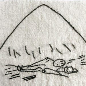 May include: Embroidered artwork on a square of off-white fabric. The black thread depicts a mountain, a figure, and other abstract shapes. The piece has a minimalist, handmade aesthetic.