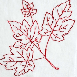 May include: A white fabric square featuring red thread embroidery of a branch with four maple-style leaves. The design is created with a simple outline stitch, showcasing the veins and jagged edges of the leaves in a single continuous red thread.
