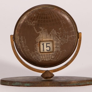 May include: A white ceramic mug with a black handle and the text "But first, coffee" in a black, handwritten-style font. The mug is on a white surface.