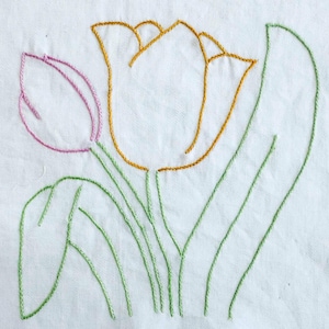 Könnte beinhalten: Gesticktes Blumendesign mit Tulpen und Blättern auf weißem Stoff. Die Tulpen sind mit gold- und rosafarbenem Faden umrandet, die Stiele und Blätter sind grün. Schlichtes, elegantes Blumendesign.
