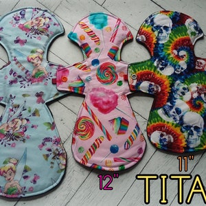 May include: Three reusable cloth pads in different patterns. The first pad is blue with a Tinkerbell design and measures 14 inches. The second pad is pink with a candy cane and lollipop design and measures 12 inches. The third pad is green, red, and yellow with a tie-dye skull design and measures 11 inches. The text "TITAN" is printed in yellow on the bottom of the image.