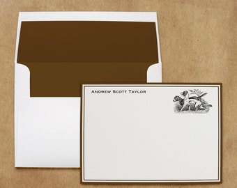 May include: Stationery set featuring a white card with a brown border and the name "Andrew Scott Taylor" printed at the top. A black and white illustration of two dogs is on the right. The envelope is white with a brown interior.