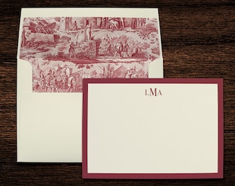 May include: A white envelope with a red and white patterned flap. The envelope is closed and has a white card inside with a red border and the monogram "LMA" printed in red.