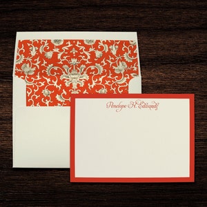 Peut inclure: Une enveloppe blanche avec un motif floral rouge et blanc sur le rabat. L'enveloppe est accompagnée d'une carte de vœux blanche avec une bordure rouge et le texte "Penelope H. Edwards" en cursive rouge.
