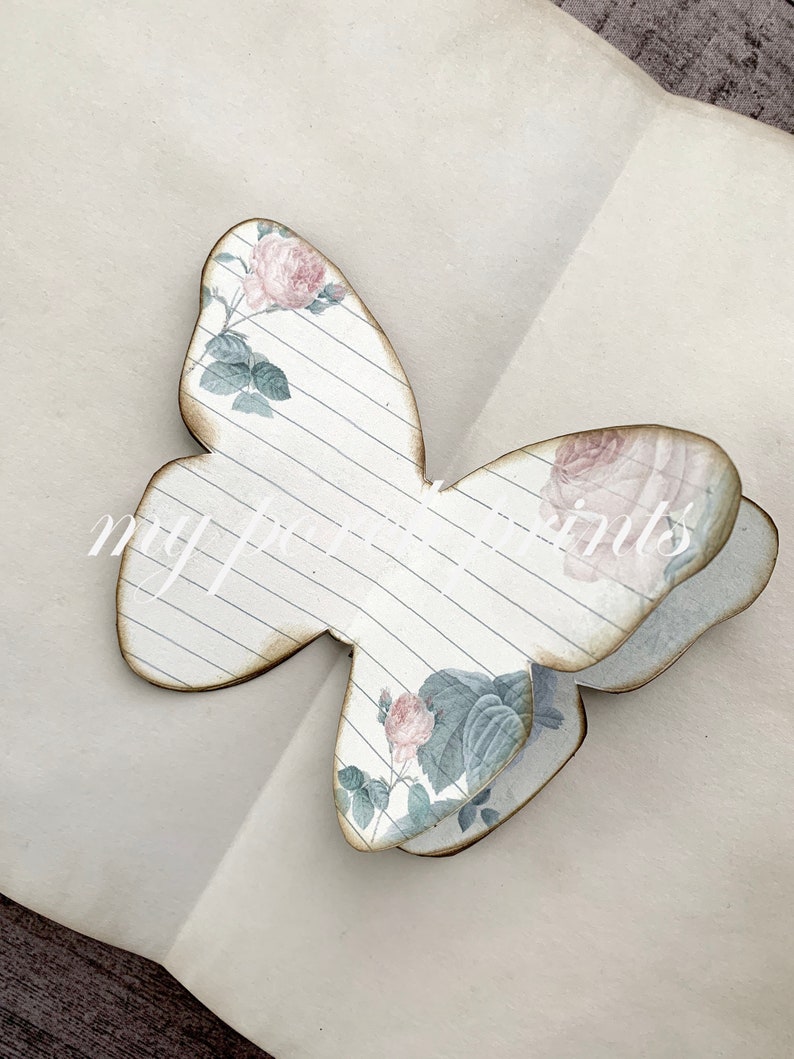 Puede incluir: Una artesan&iacute;a de papel en forma de mariposa decorativa con un patr&oacute;n floral y un dise&ntilde;o de papel rayado. La mariposa est&aacute; doblada por la mitad y tiene una est&eacute;tica vintage.