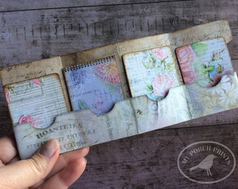 May include: A vintage-style paper craft project with a floral theme. The project features several small pockets with different floral patterns and a handwritten label that says "Roasted & Ground Coffee".