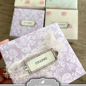 Puede incluir: Cajas de manualidades mini imprimibles con un dise&ntilde;o floral. La caja est&aacute; etiquetada "CHARMS" y mide aproximadamente 8,25 x 7,6 cm.