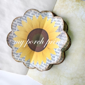K&ouml;nnte beinhalten: Eine Papier-Bastel-Sonnenblume mit gelben Bl&uuml;tenbl&auml;ttern und einer braunen Mitte. Die Sonnenblume ist aus Seiten eines Buches mit gedrucktem Text gefertigt.