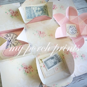 May include: A pink and white paper box with a floral design. The box is open and has several compartments. Each compartment has a different design, including a clock, a heart, and a flower. The box is perfect for storing small items or gifts.