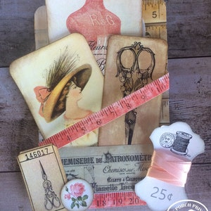 Pode incluir: Uma cole&ccedil;&atilde;o de ef&ecirc;meras de papel de estilo vintage com um tema de costura. As ef&ecirc;meras incluem uma forma de vestido rosa, um par de tesouras, uma bobina de fio, uma fita m&eacute;trica e uma rosa. O texto nas ef&ecirc;meras inclui "R&G", "TEMISERIE DU PATRONOM&Egrave;TRE", "Chemises sur Mesure", "BILETS & CALSCON", "lanelle Inco", "LEONARDO", "2025&cent;", "18 19 20" e "MY PORCH PRINTS".