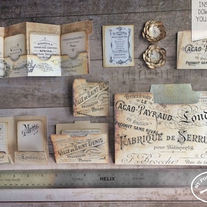 May include: A set of printable vintage-style file folder labels with French text. The labels feature a variety of designs, including a label that says "Toilet Shaving Aunde", a label that says "Cacao-Payraud en feuilles Produit sans rival", and a label that says "Ville de Saint Denis Nouveaut&eacute;s Paris".