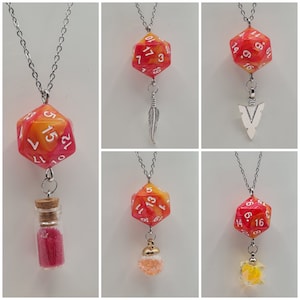 Puede incluir: Cinco collares diferentes con un dije de dados rojo y amarillo con números blancos. Cada collar tiene un dije diferente unido al dije de dados, incluyendo una pluma, una punta de flecha, una pequeña botella, una pequeña esfera de vidrio y un pequeño cubo de vidrio.
