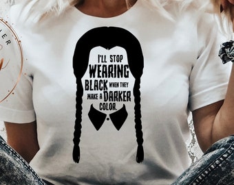 May include: A white t-shirt with a black silhouette of a girl with pigtails and the text "I'll stop wearing black when they make a darker color."