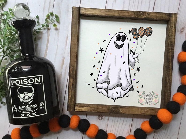 K&ouml;nnte beinhalten: Ein wei&szlig;er Geist mit einem l&auml;chelnden Gesicht h&auml;lt drei Ballons, auf denen in schwarzen und orangefarbenen Buchstaben "BOO" steht. Der Geist ist von schwarzen und violetten Konfetti auf wei&szlig;em Hintergrund umgeben.