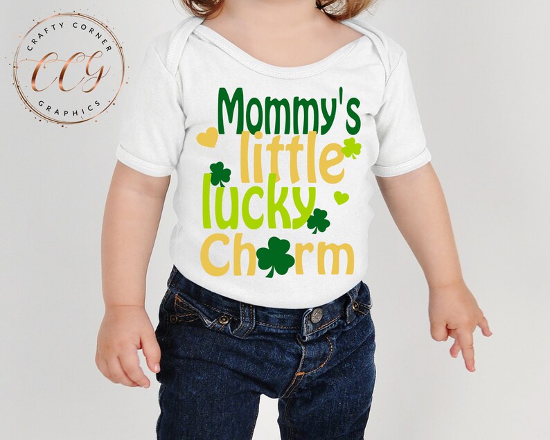May include: White baby onesie with green shamrocks and gold lettering that reads "Mommy's little lucky charm".