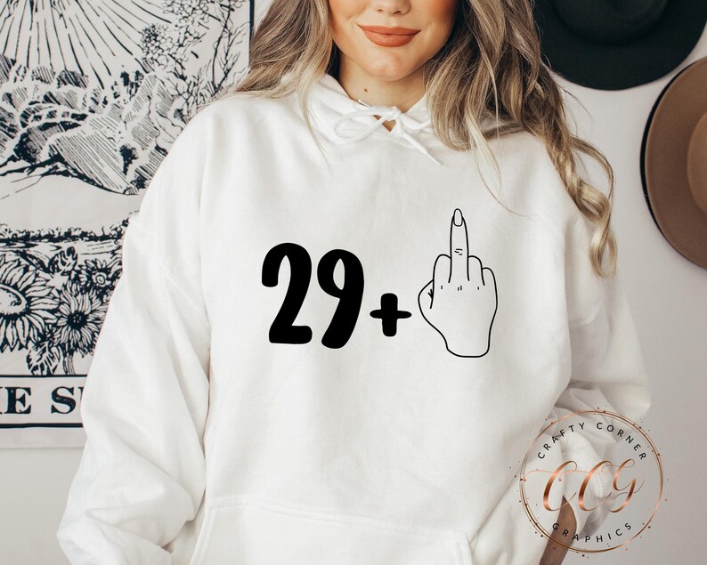 Puede incluir: Sudadera blanca con texto negro que dice "29+" y un contorno negro de un dedo medio.