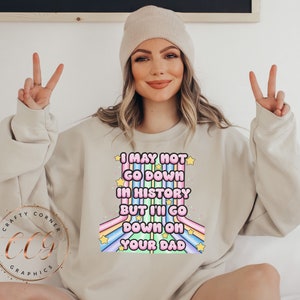 May include: A light beige sweatshirt with a rainbow graphic and the text "I may not go down in history but I'll go down on your dad".