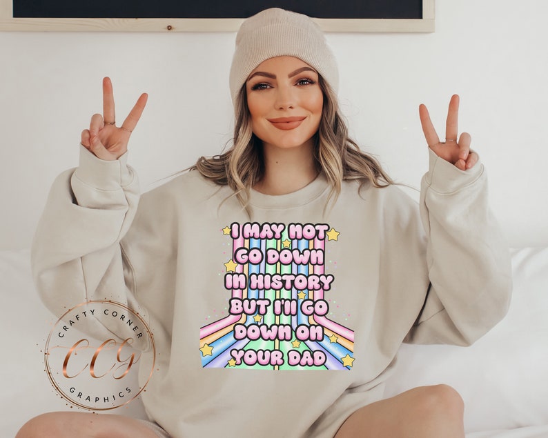May include: A light beige sweatshirt with a rainbow graphic and the text "I may not go down in history but I'll go down on your dad".