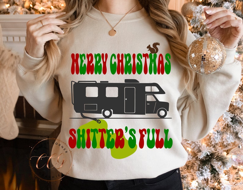May include: A white sweatshirt with a green, red and white graphic that says "Merry Christmas Shitter's Full". The graphic also includes a black and white illustration of a camper van.