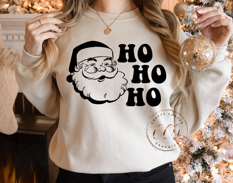 Peut inclure: Un sweat-shirt cr&egrave;me avec une illustration en noir et blanc du P&egrave;re No&euml;l et le texte "Ho Ho Ho".
