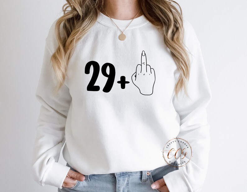 Puede incluir: Sudadera blanca con texto negro que dice "29+" y un dibujo de l&iacute;nea negra de un dedo medio.
