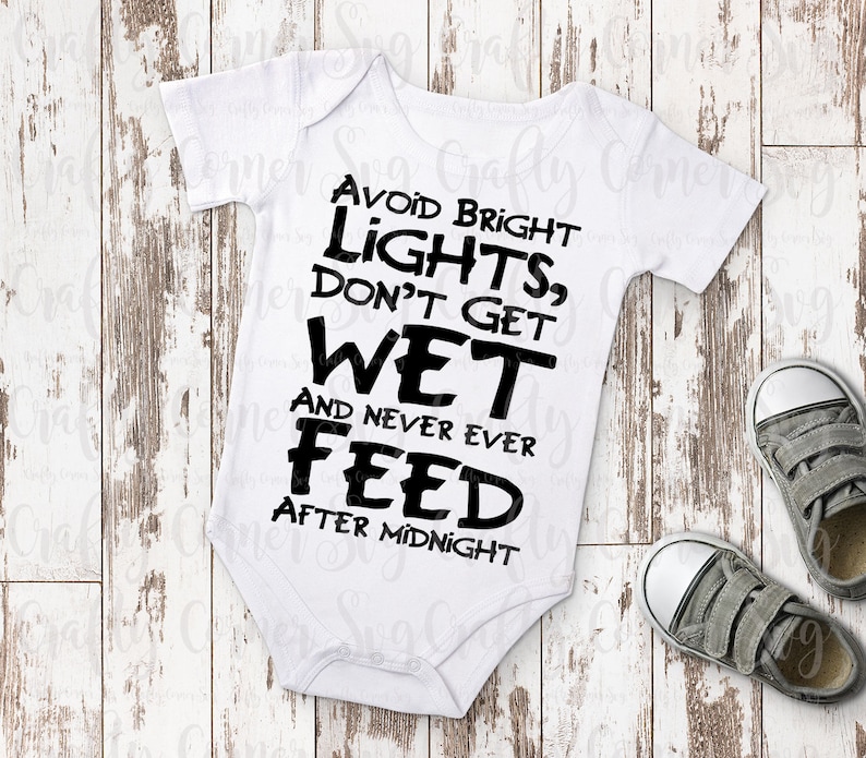 May include: White baby onesie with black text that reads "Avoid Bright Lights, Don't Get Wet And Never Ever Feed After Midnight".