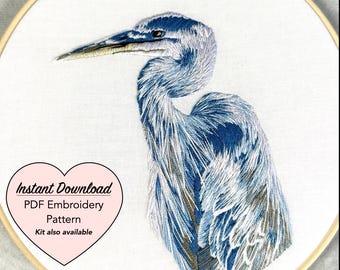 May include: An embroidery hoop featuring a detailed blue heron design. The bird is rendered with intricate stitching, showcasing shades of blue and white. The text "Instant Download PDF Embroidery Pattern" is in a pink heart-shaped graphic.