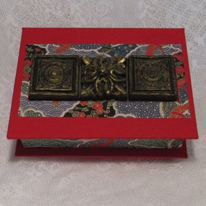 Box of Hidden Dreams with a hinged lid topped with three Black and Gold Medallions  surrounded with Red, Black, Blue and Green Washi Paper