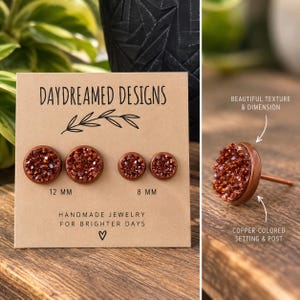 May include: Four round stud earrings with textured, dark copper-colored druzy centers set in copper-colored metal. The earrings are displayed on a tan card labeled DAYDREAMED DESIGNS with 12 mm and 8 mm size labels, and one earring is shown separately.