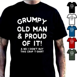 Könnte beinhalten: Schwarzes T-Shirt mit dem weißen Aufdruck "GRUMPY OLD MAN & PROUD OF IT!". Darunter steht "& NO I DIDN'T BUY THIS CRAP T-SHIRT". Zusätzliche T-Shirts in verschiedenen Farben werden ebenfalls gezeigt.