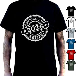 Può includere: T-shirt nero con grafica bianca che recita "OFFICIALLY 2026 RETIRED" in un design a timbro circolare. La maglietta è indossata da una persona. Ulteriori opzioni di colore della maglietta sono mostrate a destra.