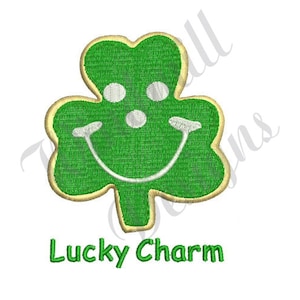 Può includere: Un trifoglio verde con un viso sorridente, contornato d'oro, con il testo "Lucky Charm" sotto.