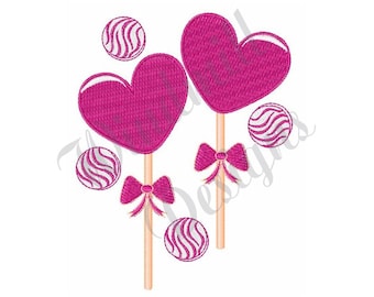 Könnte beinhalten: Zwei rosa herzförmige Lutscher mit weißen Wirbel-Bonbon-Dekorationen und rosa Schleifen auf Stielen. Vier weiße Wirbel-Bonbon-Dekorationen sind um die Lutscher herum verstreut.