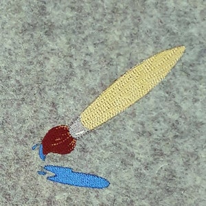 Puede incluir: Un pincel amarillo con mango rojo y pintura azul goteando de la punta. El pincel está sobre una superficie gris y ha creado una salpicadura de pintura azul.