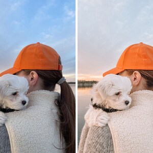 Op de afbeelding: Een vrouw met een oranje baseballpet houdt een witte, pluche hond op haar schouder. De hond kijkt naar de camera. De achtergrond is een wazig beeld van een meer en de lucht.