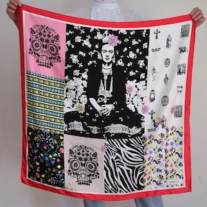 May include: A red silk scarf with a patchwork design featuring a black and white portrait of Frida Kahlo, a zebra print, and several skull motifs. The scarf has a red border and the text "COQUELICOT" in the bottom right corner.