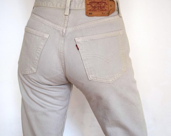 May include: A pair of light beige denim jeans with a brown leather patch on the back pocket that says "Levi's Strauss & Co. San Francisco. Cal. 90102".