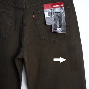 May include: A pair of dark brown relaxed fit jeans with a Levi's 550 label on the back pocket. The jeans have a relaxed fit and a straight leg. The jeans are made of 100% cotton.