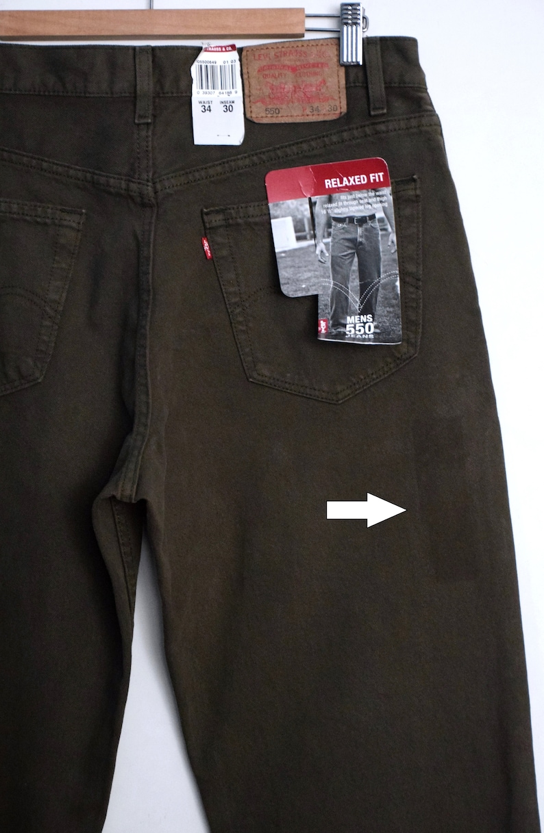 May include: A pair of dark brown relaxed fit jeans with a Levi's 550 label on the back pocket. The jeans have a relaxed fit and a straight leg. The jeans are made of 100% cotton.