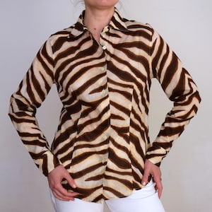 Pode incluir: Uma camisa de botões de manga comprida com estampa de zebra em marrom e branco.