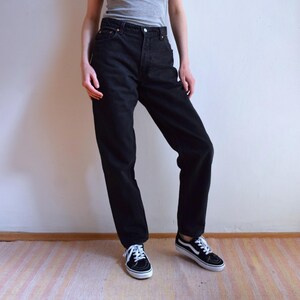 Peut inclure: Jean en denim noir avec une coupe droite classique. Le jean a une fermeture boutonn&eacute;e et zipp&eacute;e, cinq poches et un d&eacute;lavage fonc&eacute;. Le mod&egrave;le porte des baskets noires et blanches. V&ecirc;tements d&eacute;contract&eacute;s.