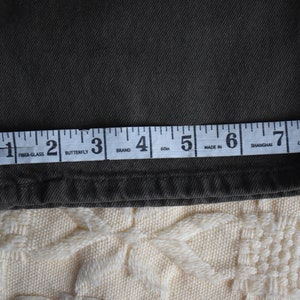 May include: Close-up of a dark green fabric with a measuring tape across it. The tape reads "Fiber-Glass, Butterfly, Brand, 60m, Made In, Shanghai, China".