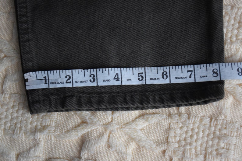 May include: Close-up of a dark green fabric with a measuring tape across it. The tape reads "Fiber-Glass, Butterfly, Brand, 60m, Made In, Shanghai, China".