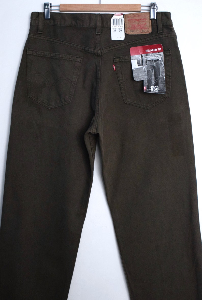 May include: A pair of dark brown relaxed fit jeans with a Levi's tag on the back pocket. The tag says "Men's 550 Relaxed Fit".
