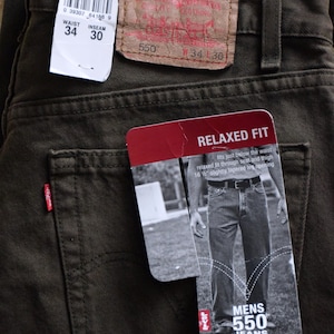 May include: A pair of dark green jeans with a brown leather Levi's label and a white tag with the size information: Waist 34, Inseam 30. The jeans have a relaxed fit and are labeled as Men's 550 Jeans.