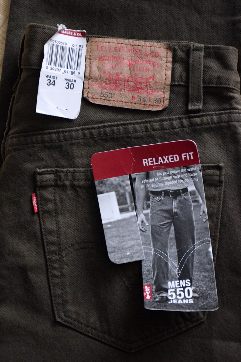 May include: A pair of dark green jeans with a brown leather Levi's label and a white tag with the size information: Waist 34, Inseam 30. The jeans have a relaxed fit and are labeled as Men's 550 Jeans.